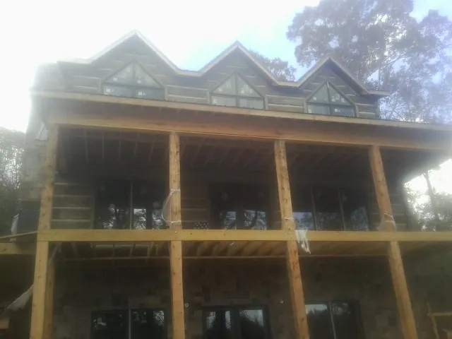 Dormers and porch framing on a large log home under construction — Roof Coating work by our crew in Plymouth
