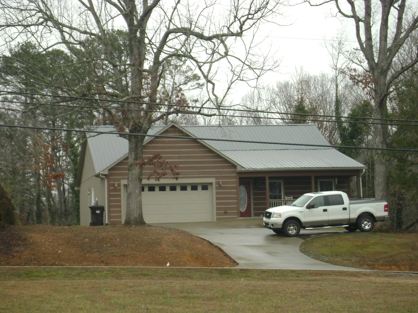 Gray metal roof on a log sided house with an attached two car garage in Plymouth